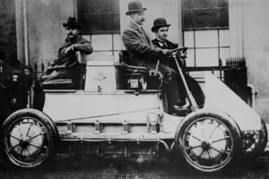 1900年にローナー・ポルシェで運転手の隣に座っているフェルディナント・ポルシェ。