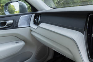 ボルボXC60：エレガントなセンターコンソールのシャッターは、デコラティブパネルと同素材（ウッドパネル）で作られており、その下には、新しい2＋1カップホルダーを備えている。改良されたワイヤレス・スマートフォンチャージは、トンネルエリアの前方に移動され、使い勝手が大幅に向上。