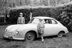ポルシェ356/2クーペの中に乗っているのはフェリー・ポルシェ。奥の左はフェルディナント・ピエヒで、クルマ手前はその弟のハンス・ミヒャエル・ピエヒ。