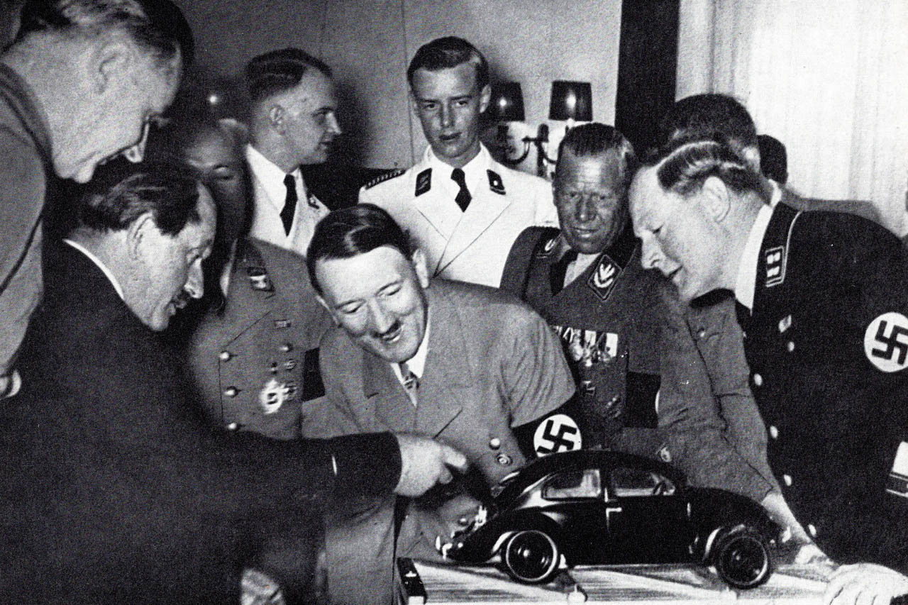 ポルシェ博士はフォルクスワーゲン・プラモデルを1938年ヒトラーの誕生日にプレゼントし熱心に説明（ナチス幹部室内）。