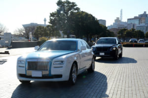 朝日を全身に浴びながら会場に進入してくるロールス・ロイス・ゴーストとベントレー・ベンテイガ。