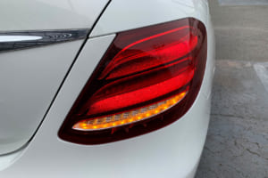 再発進時にドライバーがハザードランプ点滅中、ウインカーレバーを操作し走行車線の右側に進入する意思を示すと、メルセデス・ベンツは右側ウインカーのみ点滅する。拡大写真はEクラス／W213のリアウインカー点滅中。