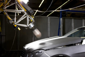 2009年5月発売のEクラス／W212には、「アクティブボンネット」を採用。歩行者と衝撃が発生すると、フロントバンパー内のセンサーが感知し、スプリング式のエンジンフードの後端が瞬時にして約5cm持ち上がる。従って、エンジンフードとエンジン間の空間が広がり、歩行者が受ける衝撃をさらに緩和。写真はボンネットに衝撃を加えたテスト。